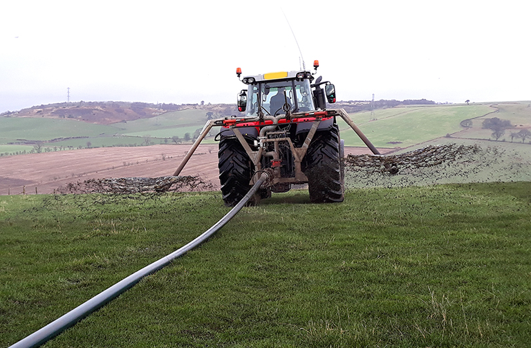 tractor spreading slurry on a field