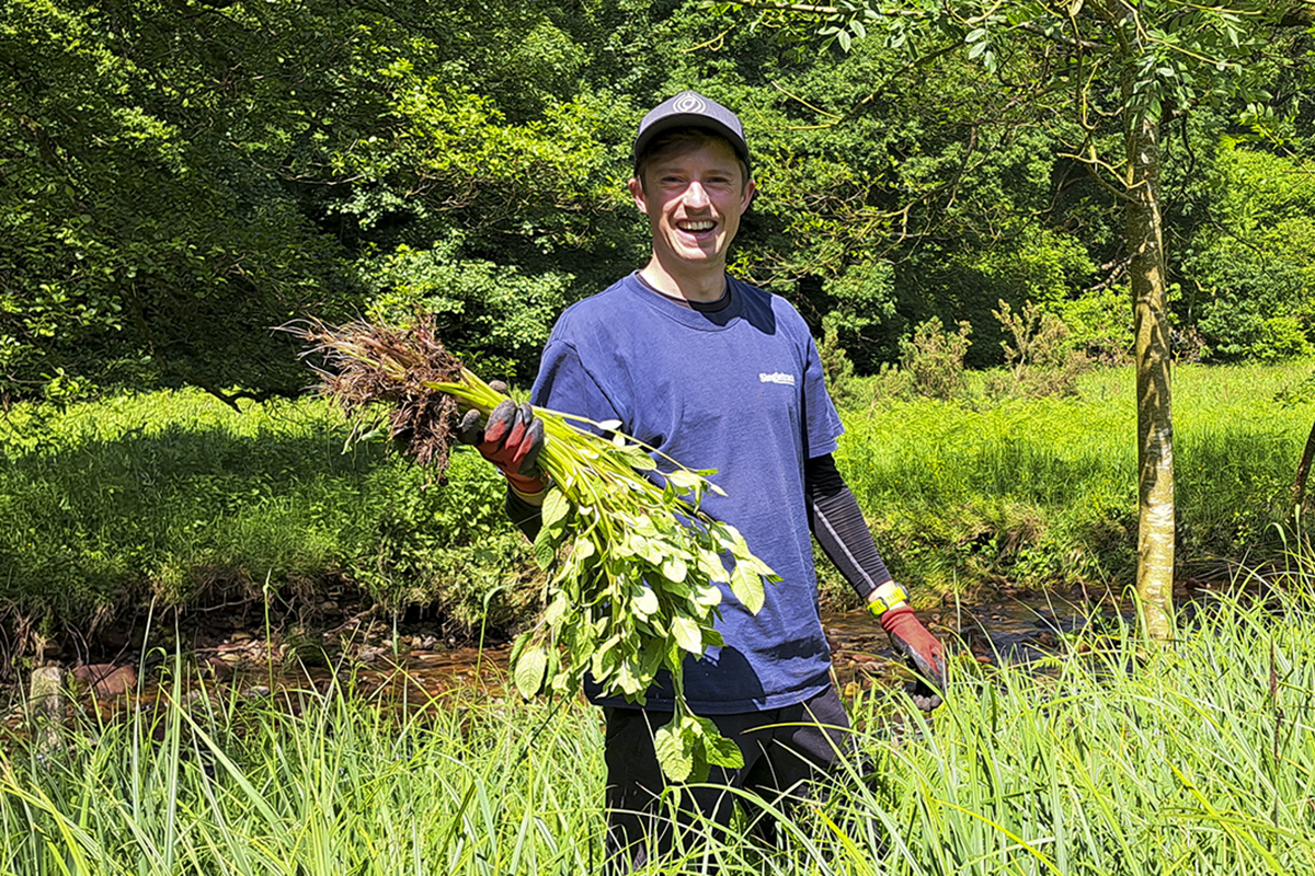 Ali holding a bunch of Himalayan balsam plants
